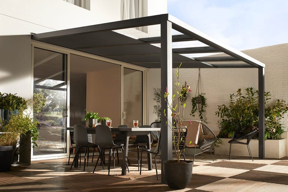 Terrasse unter einem anthrazitfarbenen Terrassendach mit gedecktem Esstisch und Pflanzen