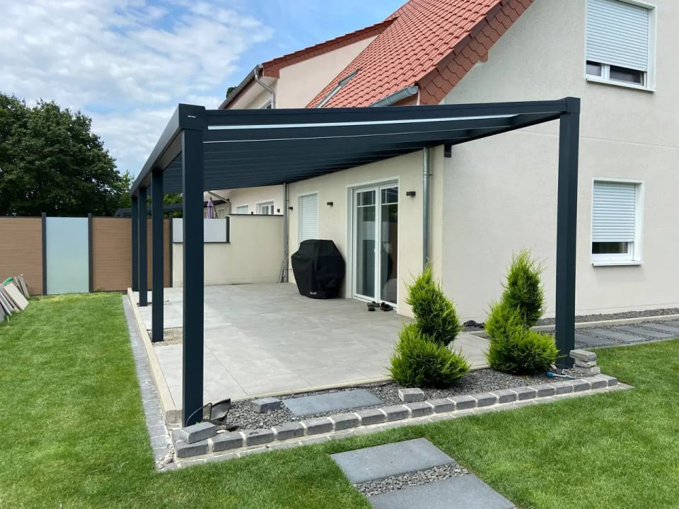 Anthrazitfarbenes Terrassendach über einer Terrasse mit Rasen