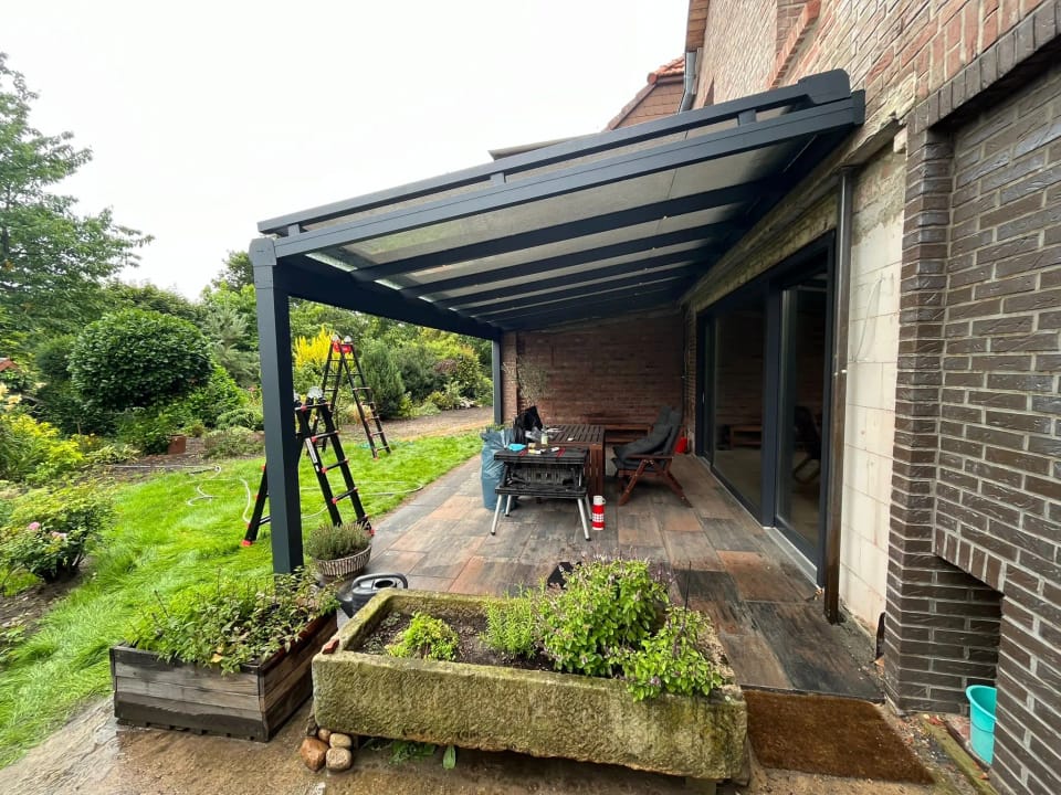 Terrassendach Green-400 mit Glasdach an einem Klinkerhaus